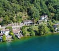 Luxury villas on the shores of a lake, surrounded by greenery, with access roads, a dock, and a pier.