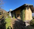 Raised ground floor house, yellow exterior, green ivy, mountain view