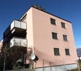 Apartment building, pink facade, 5 floors, balconies on each floor, mountains in the background