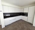 modern kitchen, white cabinetry, black countertops, integrated appliances, under cabinet lighting, open shelving, stainless steel hardware