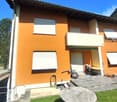 2-story house with orange exterior, white windows, balconies, and a stone feature in the front yard