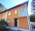 2-story orange house with large windows, balcony, and stone patio in front of the house