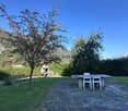 Outdoor dining table, bench, fireplace, hedges, grassy area, mountain view
