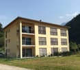 Yellow apartment building, multiple balconies, modern design, 2 floors, mountain view, car parked in front