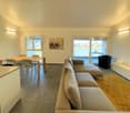 modern living room with large windows, beige sofa, dining table, TV, carpet, white walls, modern decor