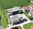 two story house, large modern architecture, multiple houses around, solar panels on roof, garage with multiple cars, large front yard, garden and trees