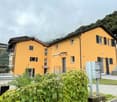 2 story building, yellow wall, black shutter, fenced area, balcony