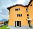 3 story house, yellow wall, gray ground floor, balconies, terrace