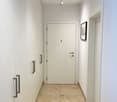 An empty corridor with a white door, two closets, a picture frame on the wall, and tiled flooring.