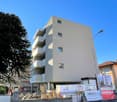 multi-story building under construction, concrete structure, balconies on upper floors, street lights, construction materials