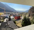 Aerial view of town with many buildings, red house, crane, mountains, trees, sky