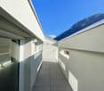 Balcony with tiled floor, glass doors, railing, distant mountain view