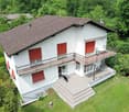 2 story house, white paint, brown roof, balconies, red shutters, dog in the foreground