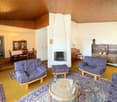 living room with blue sofas, round coffee table, dining area with table, chairs and cabinet, wooden ceiling, fireplace
