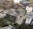 Aerial view of a multi-story building with solar panels on the roof, balconies, and a parking area.