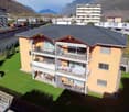 3 story house, orange exterior, multiple balconies, located in a residential area with a view of the mountains