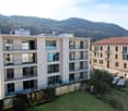 Modern apartment building with multiple balconies, located in a scenic area with a mountain view