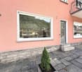 Pink building with a balcony, large window, and a small plant in front
