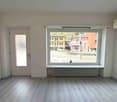 empty room, white walls, wooden floor, large window, white door, radiator
