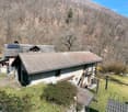Stone house, brown roof, solar panels, surrounded by trees, mountain view