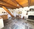 kitchen with stone floor, wooden ceiling, fireplace, dining table, wooden stairs