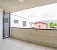 Modern balcony with white tiles, concrete parapet, metal railing