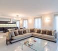 white walls, glass table, white tiles, sectional sofa, beige cushions, living area