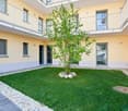 Balconies with railings, a small garden, well-maintained grass and shrubs, and walkways