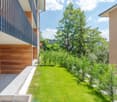 Building exterior with metal railing, wooden wall, small garden