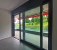 Large sliding glass doors with a view of a green outdoor area, hardwood floors, minimalist decor