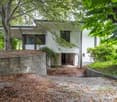 2 story house, white paint, elevated ground floor, tree-lined surroundings
