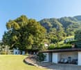 detached house with staircase, garage, open green area, mountains in the background
