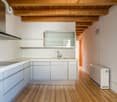 Spacious kitchen with white cabinets, wooden beams on the ceiling, hardwood flooring, and a dishwasher visible.