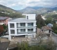 Newly built modern white house, glass balconies, open view of the mountains, unfinished road