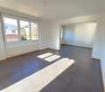 Empty room, grey tiled floor, white walls, large windows, radiator