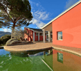 Modern villa with swimming pool, red walls, large entrance, pillar, patio, red brick floor, greenery, mountain view