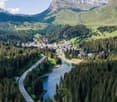 Panoramic aerial shot of scenic mountain valley with road, river, and village.