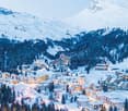 Mountain village at base of snow covered mountain, snow blanketing landscape, clusters of buildings