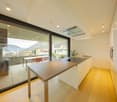 modern kitchen with large windows, wooden floor, island with sink and stove, balcony with table and chairs