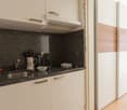 Compact kitchen with black granite countertop, stainless steel sink, built-in dishwasher, and various kitchen utensils and appliances