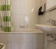 Tiled bathroom with a white sink, shower curtain, and a towel rack