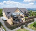 2 story house, beige exterior, gray roof, multiple balconies, garden, covered terrace