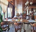 tables, chairs, glass windows, lamps, white tiled floor, potted plants, counter with bottles