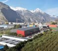 A large commercial building complex with several buildings, mountains in the background, large open areas, and cars parked in front.