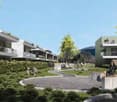 The image shows a modern residential complex with multiple buildings featuring balconies and terraces. The complex is surrounded by lush greenery, including trees and landscaped gardens. There are people walking through the central courtyard area, which h