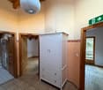 Empty room with wooden beam ceiling, white wardrobe, tile floor, wooden doors, emergency exit sign, power outlet