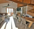 wooden ceiling, modern living room, dining area, glass windows, open staircase, kitchen, couch, TV, table, chairs, cabinet, lamp, rug, and picture