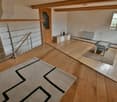 open floor plan, wooden floor, white walls, rug, glass table, metal handrail, balcony, radiator