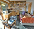 open plan living room, large couch, tv stand, wooden shelves, balcony, desk, lamp, wooden chair