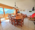 wooden table, chairs, open sliding glass doors leading to balcony, chandelier, white walls, white tiled floor, wooden ceiling, wooden shelves